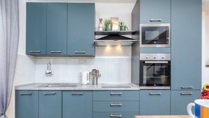 A modern kitchen with blue cabinets, a stainless steel sink, and a built-in oven.