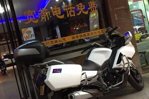 A motorcycle parked in front of a building with a sign that includes the text 'WiFi' and 'free.'