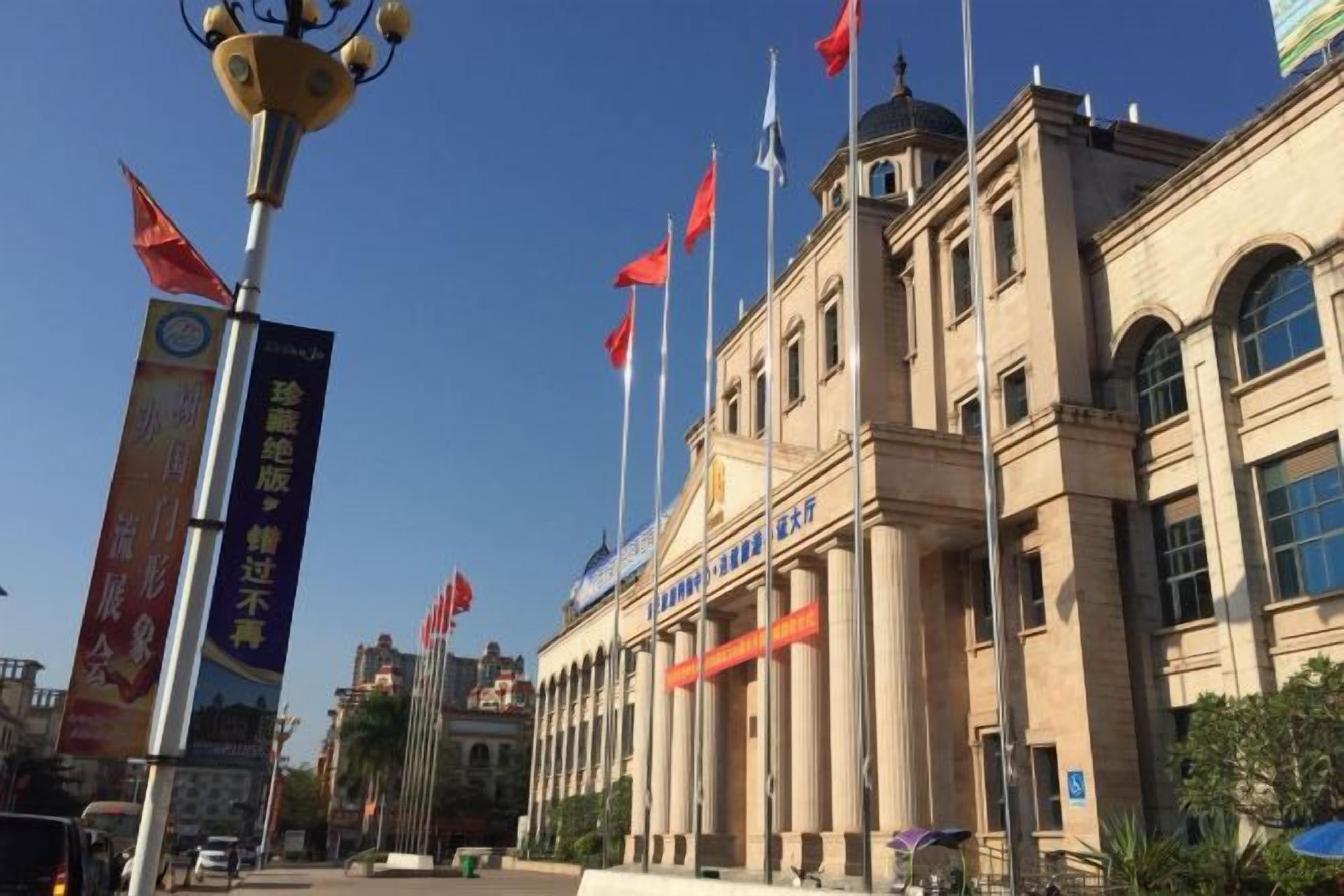 A large building with multiple flags, a prominent entrance, and a clear sky.
