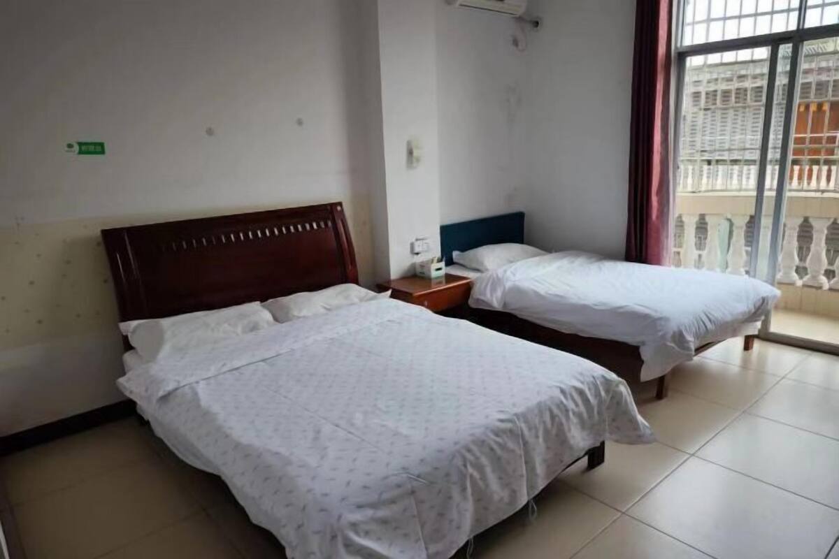 A hotel room with two beds, a window with a view, and a small bedside table.