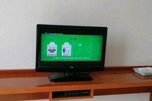 Uma TV TCL sobre um suporte de madeira com uma tela verde exibindo ícones e texto.
