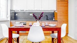 Eine moderne Küche mit weißen Schränken, einem Holztisch und weißen Stühlen.
