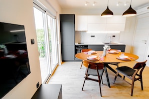 A modern kitchen with a dining area, featuring a wooden table, chairs, and pendant lighting.
