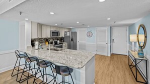 Eine moderne Küche mit Granit-Arbeitsplatten, Barhocker und Edelstahlgeräten.