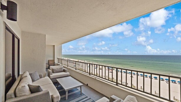 Ein Balkon mit Blick auf den Strand, einer Couch und einem Tisch.