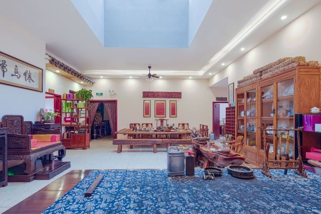 A spacious room with a high ceiling, a large window, and a traditional wooden cabinet.