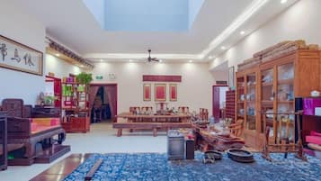 A spacious room with a high ceiling, a large window, and a traditional wooden cabinet.