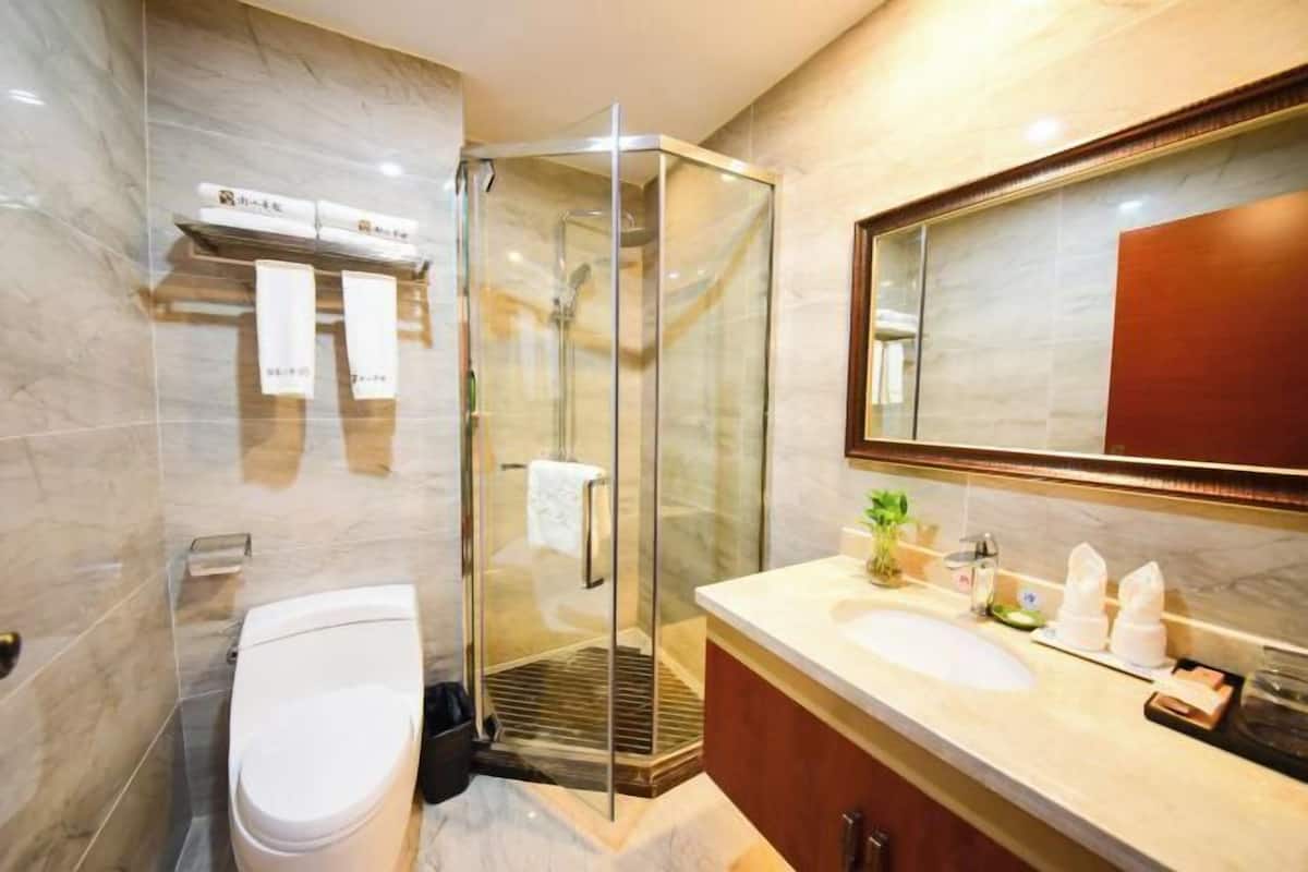 Une salle de bain moderne avec une douche à parois de verre, des toilettes blanches, un lavabo avec un miroir et un porte-serviettes.