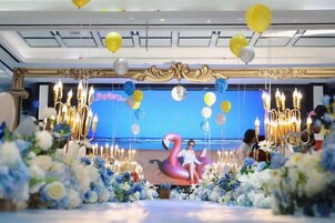 A decorated event space with a stage, floral arrangements, and balloons.