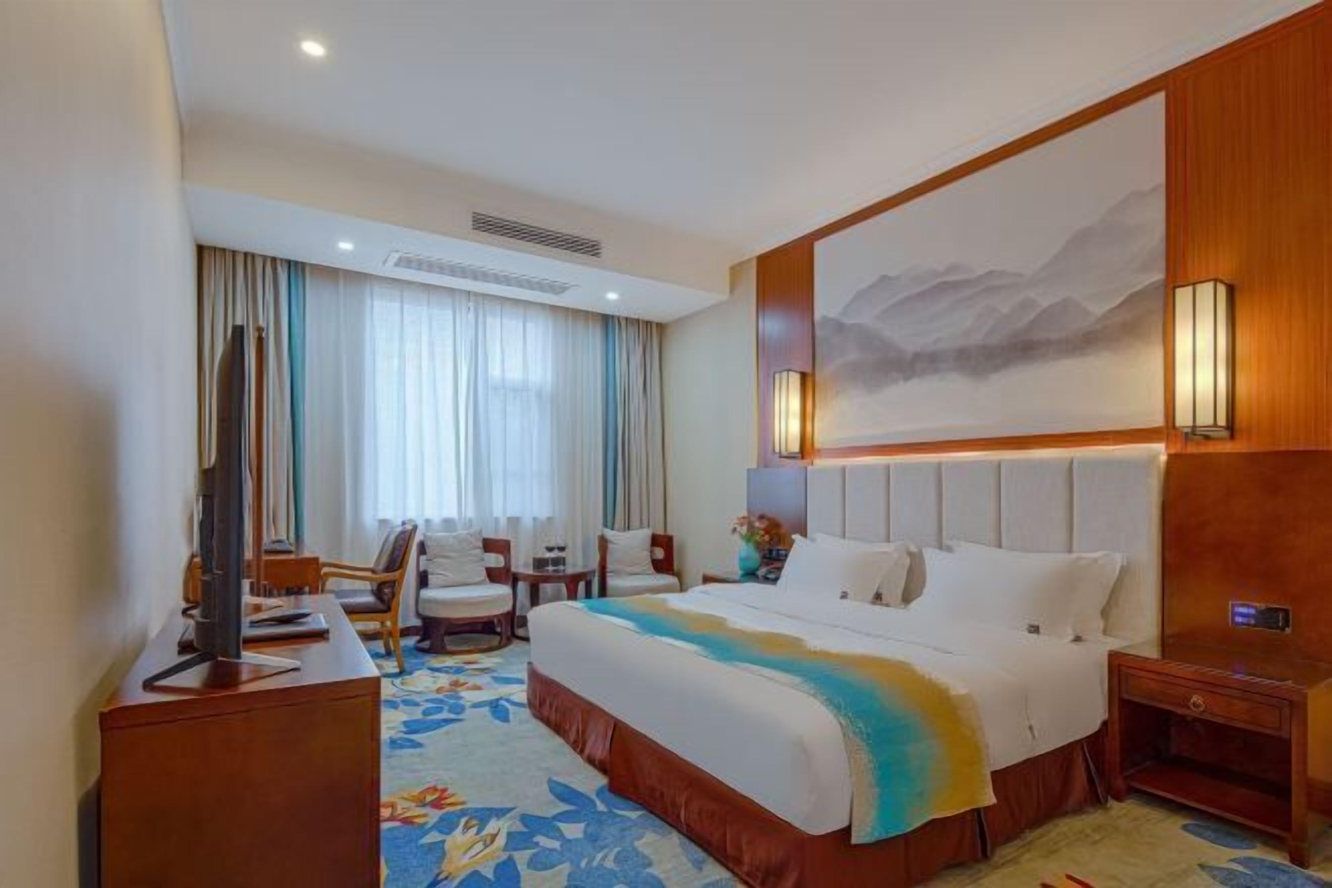 Habitación de hotel con una cama grande, televisión, escritorio y silla.