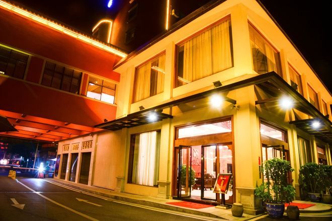 A hotel with a two-story structure, a covered entrance, and potted plants outside.