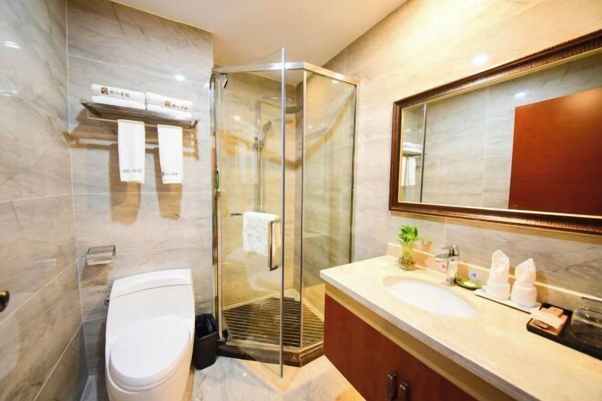 Une salle de bain moderne avec une douche à parois de verre, des toilettes blanches, un lavabo avec un miroir et un porte-serviettes.