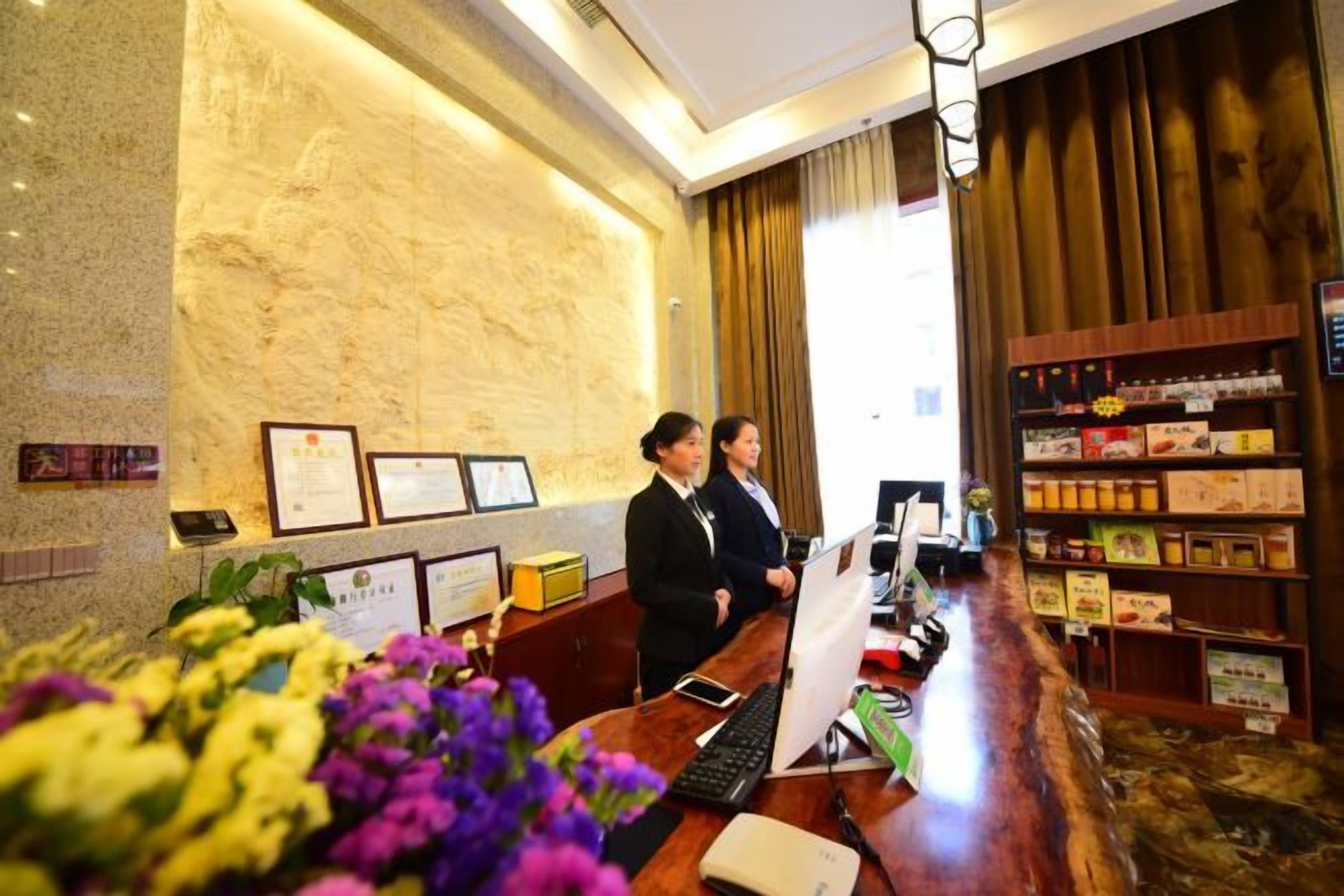 A reception desk with a computer, a telephone, and a display screen. There are framed certificates on the wall behind the desk.
