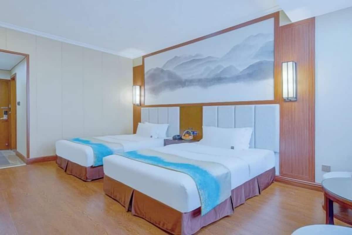 Une chambre d’hôtel avec deux lits, un tableau au mur et un plancher en bois.