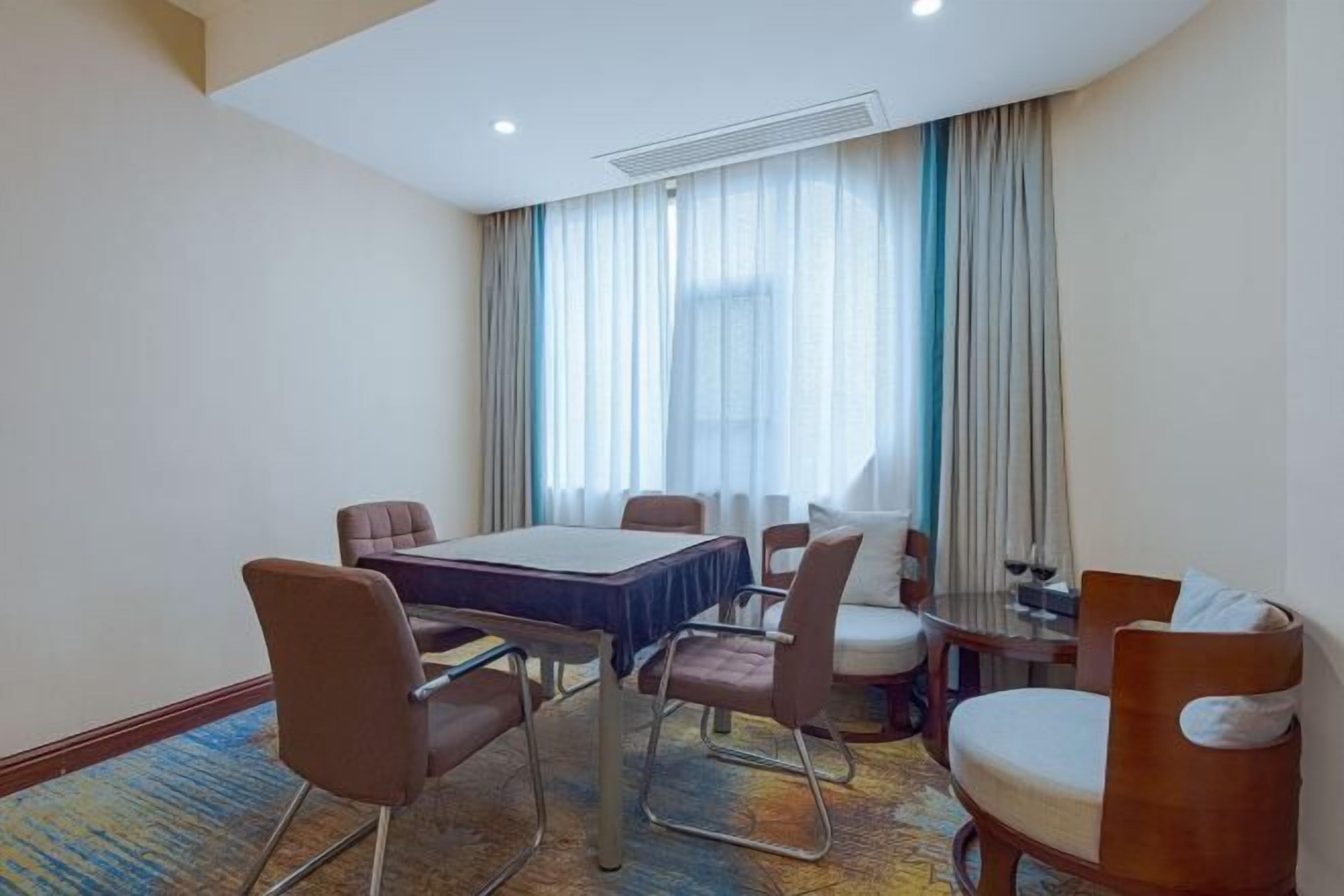 A hotel room with a dining table, chairs, a sofa, and a small side table.