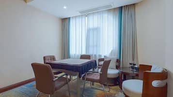 A hotel room with a dining table, chairs, a sofa, and a small side table.