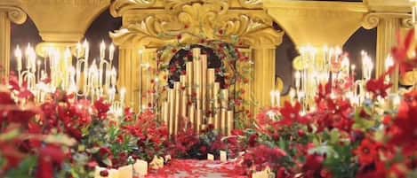 An ornate archway with candles and floral decorations, leading to a seating area.