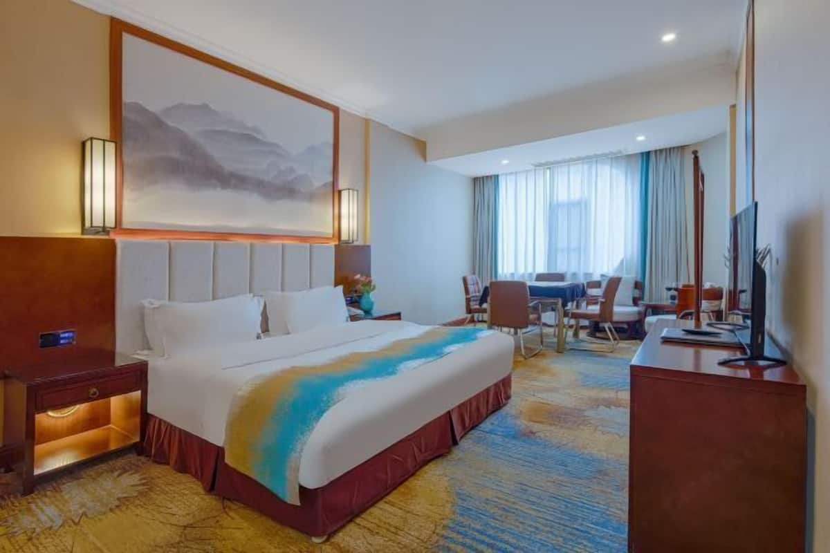 Une chambre d’hôtel avec un grand lit, un bureau et une chaise.