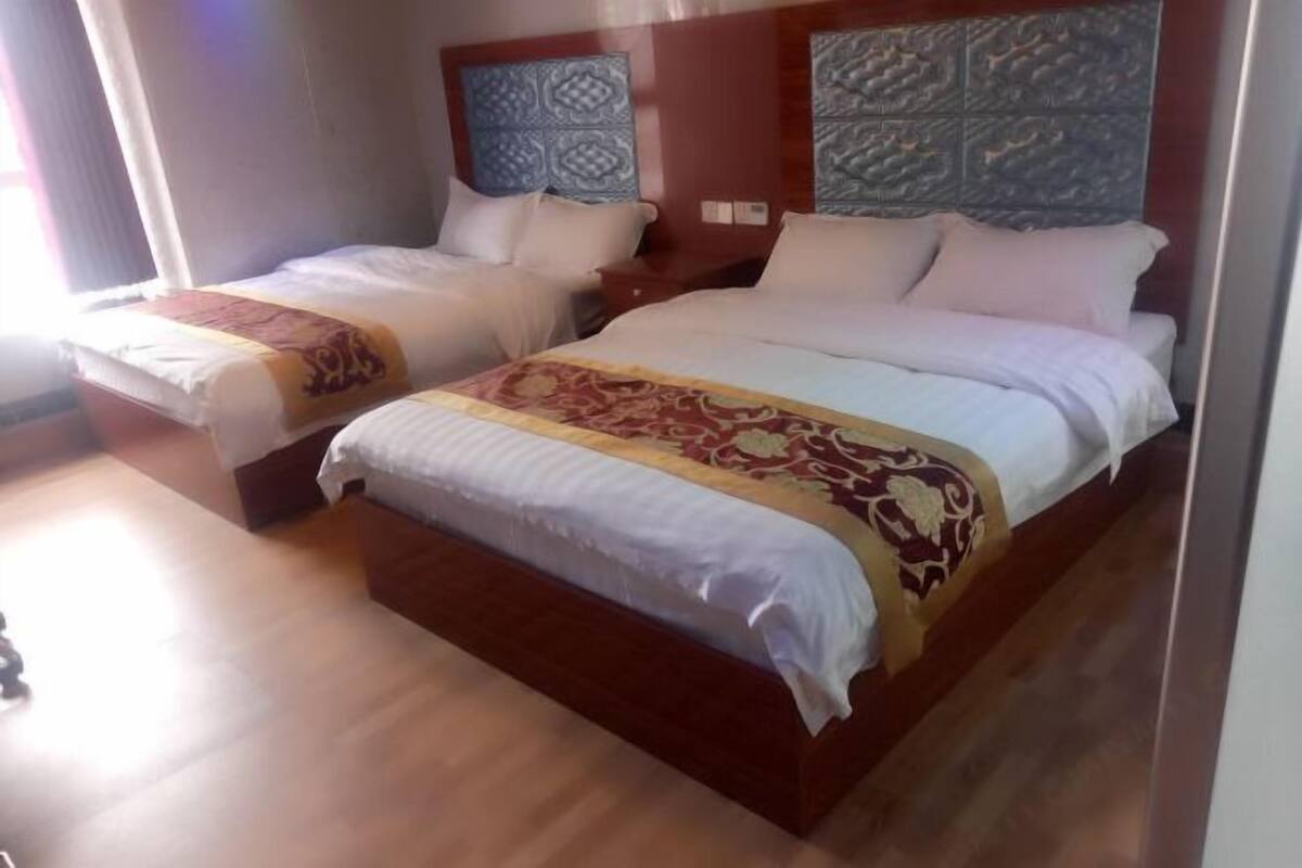 Dos camas con cabeceros, suelo de madera y pared con estampado.