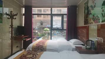 A hotel room with two beds, a desk with a chair, a television, and a window with curtains.