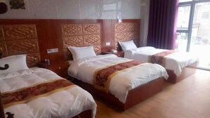 Una camera d'albergo con tre letti, ognuno dotato di una testiera in legno e biancheria da letto bianca.