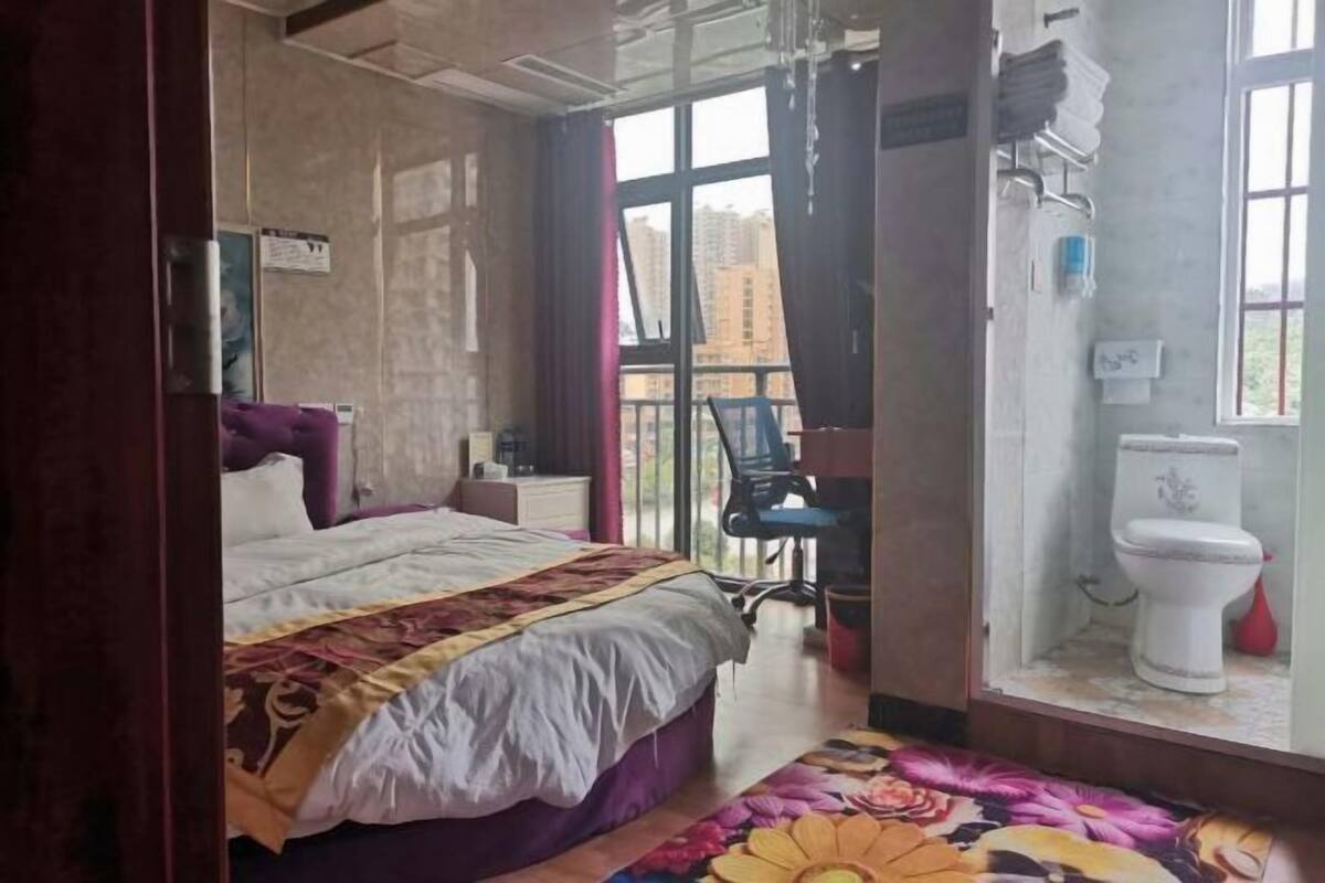 Un dormitorio con cama, una silla, una ventana y un inodoro.