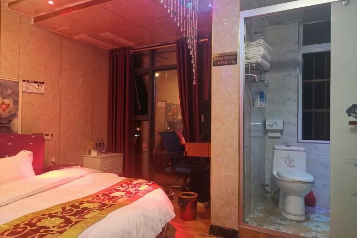 Une chambre d’hôtel comprenant un lit, un bureau, une chaise, ainsi qu’une salle de bain avec des toilettes et une douche.