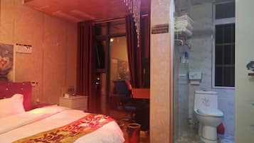 A hotel room with a bed, a desk, a chair, a bathroom with a toilet and a shower.