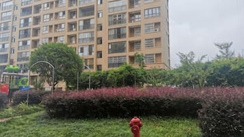 A red fire hydrant in a grassy area with a building in the background.