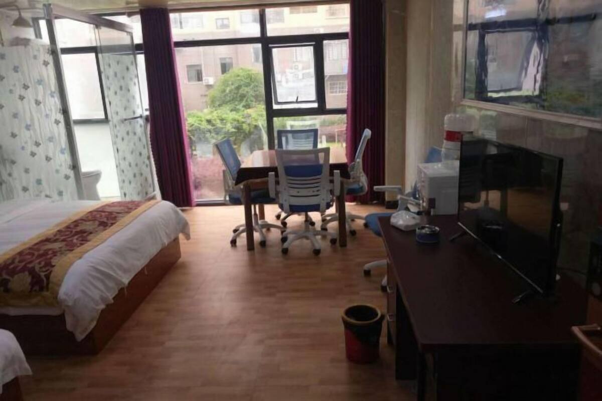 Habitación de hotel con cama, escritorio con computadora, silla y ventana con cortinas.