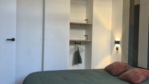 Un dormitorio moderno con una cama, un armario y una estantería en la pared.