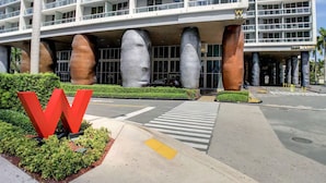 Un hôtel moderne doté d’une architecture originale, caractérisée par de grandes colonnes cylindriques et un logo rouge en forme de « W » bien visible.