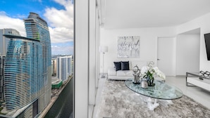 Un appartement moderne avec une table en verre, un canapé blanc et une vue sur les toits de la ville.