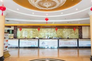 A hotel lobby with a reception desk, a large chandelier, and red lanterns. - Yintan Hotel (Rushan)