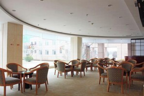A conference room with round tables and chairs, large windows, and a view of buildings outside. - Yintan Hotel (Rushan)