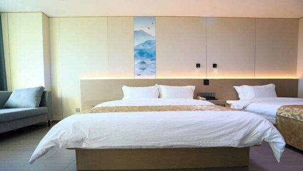 A hotel room with a large bed, a sofa, and a wall-mounted artwork.