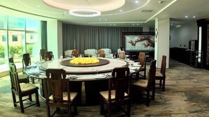 A modern dining area with a round table, wooden chairs, and a central floral arrangement.