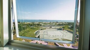 A view from a window of a circular building with a central open space, surrounded by greenery and a clear sky.