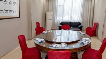 Uma sala de conferência com uma mesa redonda, cadeiras vermelhas e um sofá preto.