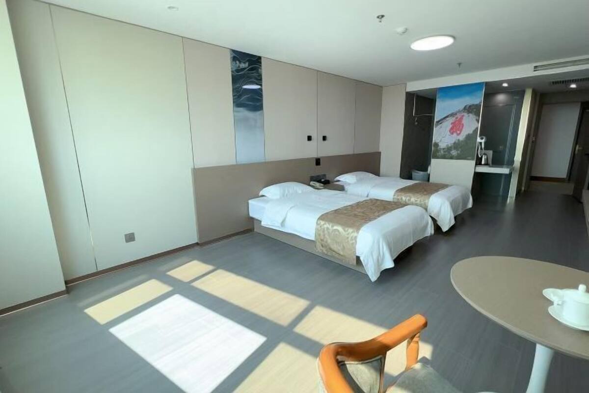 Habitación de hotel con dos camas, una mesa de comedor y una silla.