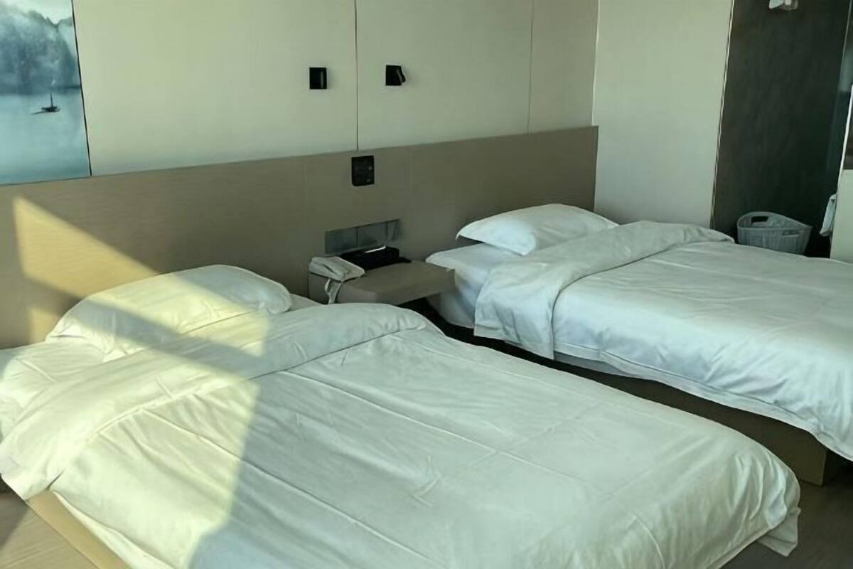 Una habitación de hotel con dos camas, un escritorio, un teléfono y un ventanal pequeño.