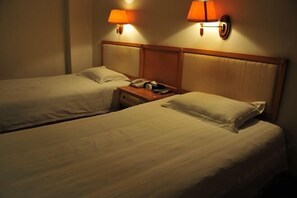 A hotel room with two single beds, each with a wooden headboard and a bedside table with a lamp. - Yintan Hotel (Rushan)