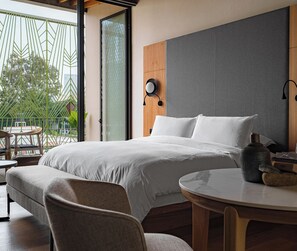 A modern bedroom with a large bed, a round table, and a view of greenery outside. - Colima 71 Casa de Arte Hotel (Mexico City)