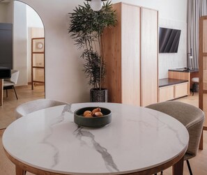 A modern living room with a round marble table, a potted plant, and a television mounted on the wall. - Colima 71 Casa de Arte Hotel (Mexico City)