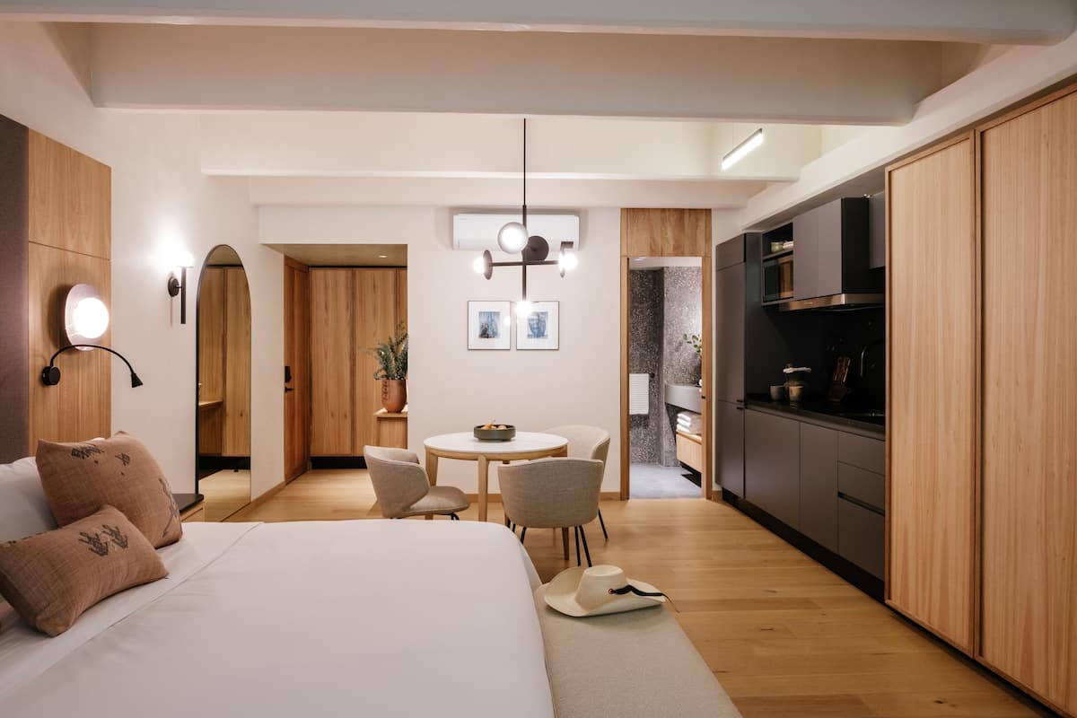 Una habitación de hotel moderna con una cama grande, una zona de comedor y una kitchenette.