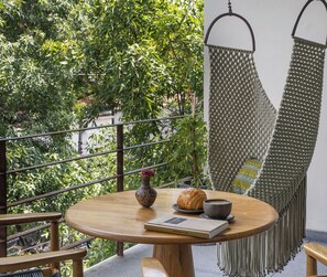 A round wooden table with a book, a vase, and a croissant on it. - Colima 71 Casa de Arte Hotel (Mexico City)