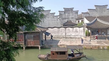 A traditional wooden boat on a river, surrounded by old-style buildings with tiled roofs.