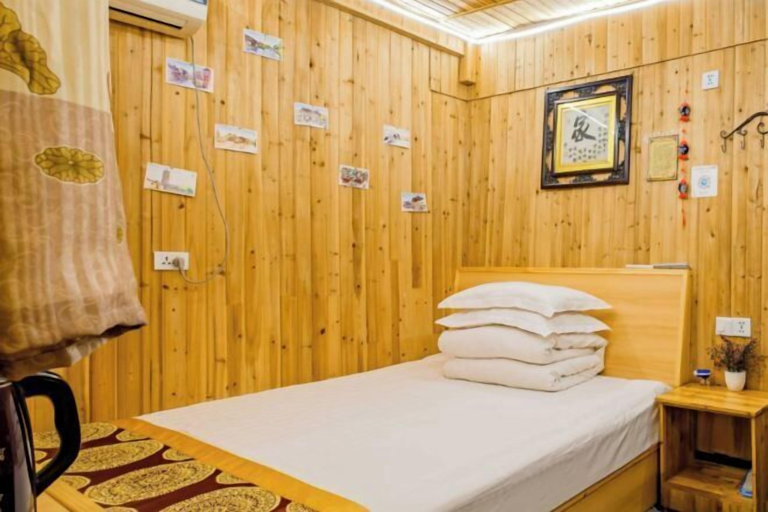 Una habitación con paneles de madera, una cama, una mesita de noche y un reloj en la pared.