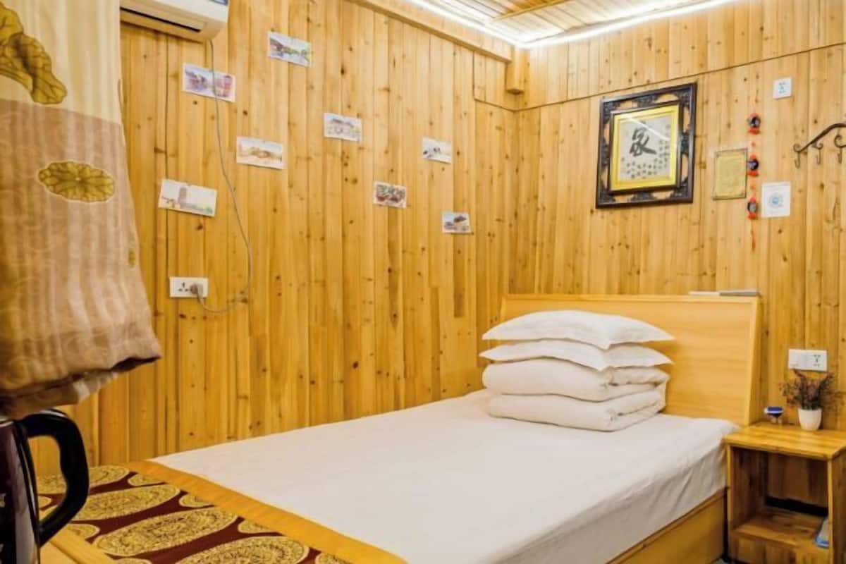 Una habitación con paneles de madera, una cama, una mesita de noche y un reloj en la pared.