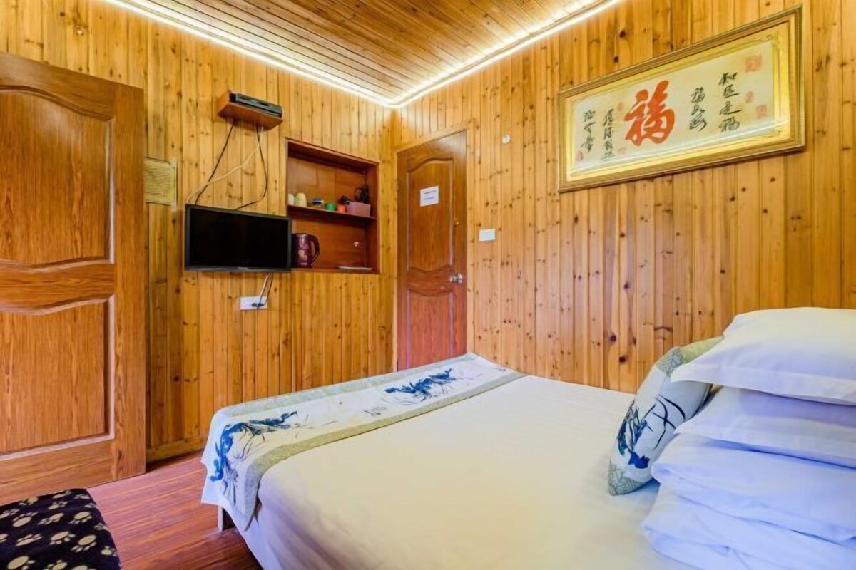 Une pièce en bois avec un lit, un téléviseur fixé au mur et une enseigne avec des caractères chinois.